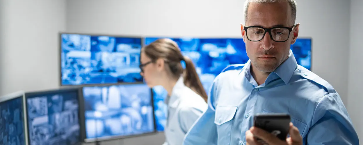 People reviewing security screens in a monitoring room.