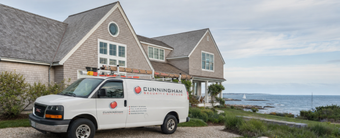 Cunningham Security Systems service van outside a New England coastal home overlooking the ocean”