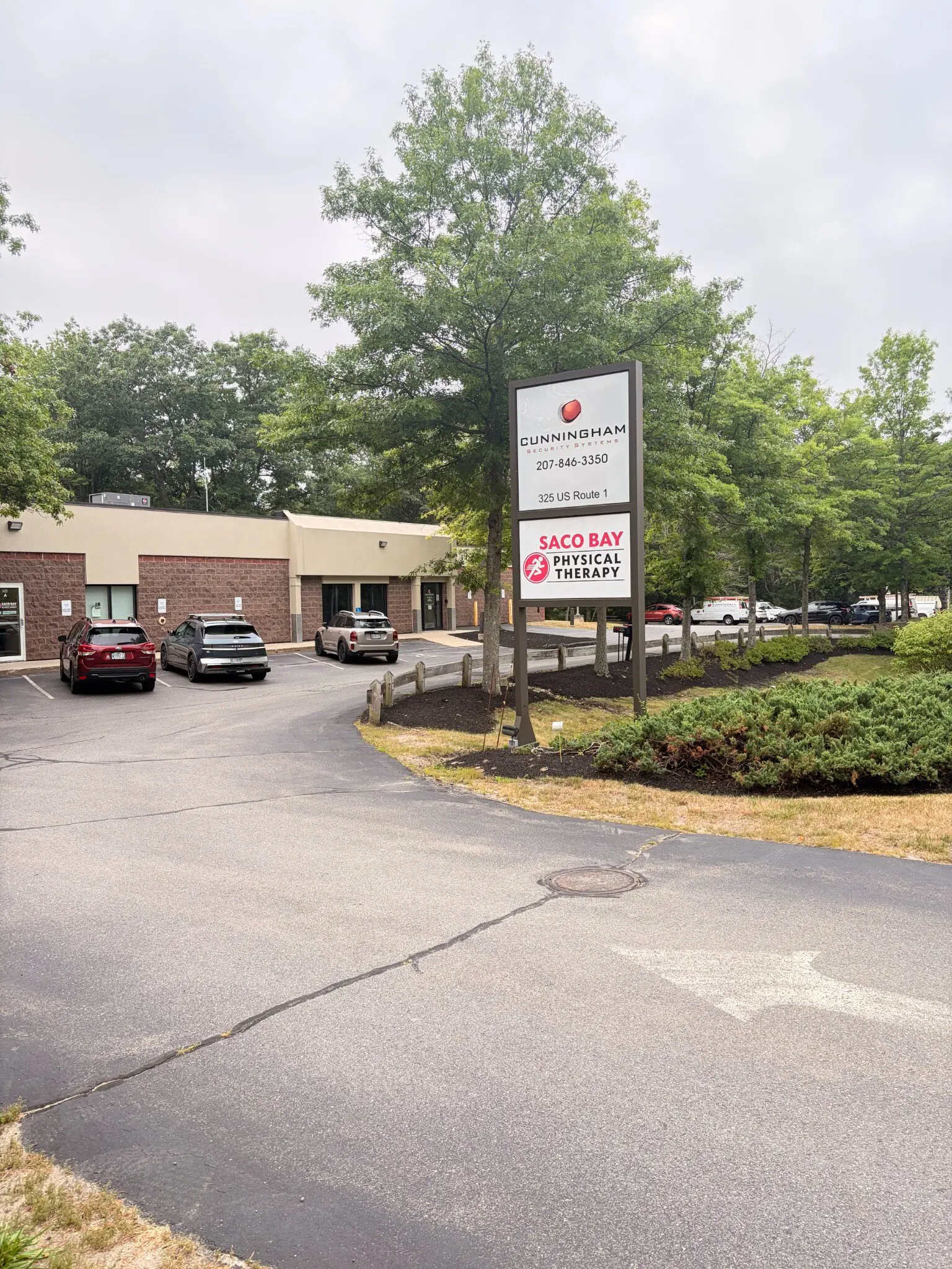 The Cunningham Security Systems building at 325 US Route 1 in Falmouth seen from the parking lot, with the roadside sign and marked vans in the background