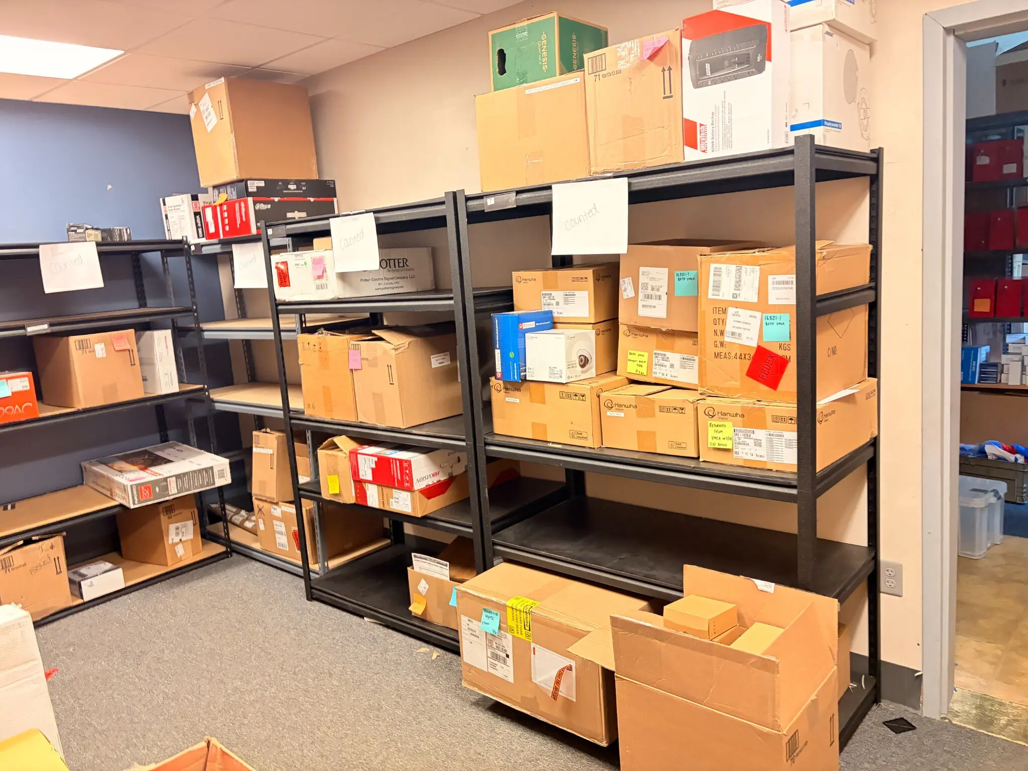 Stock shelves at the Falmouth office holding boxed cameras, fire alarm devices and cable