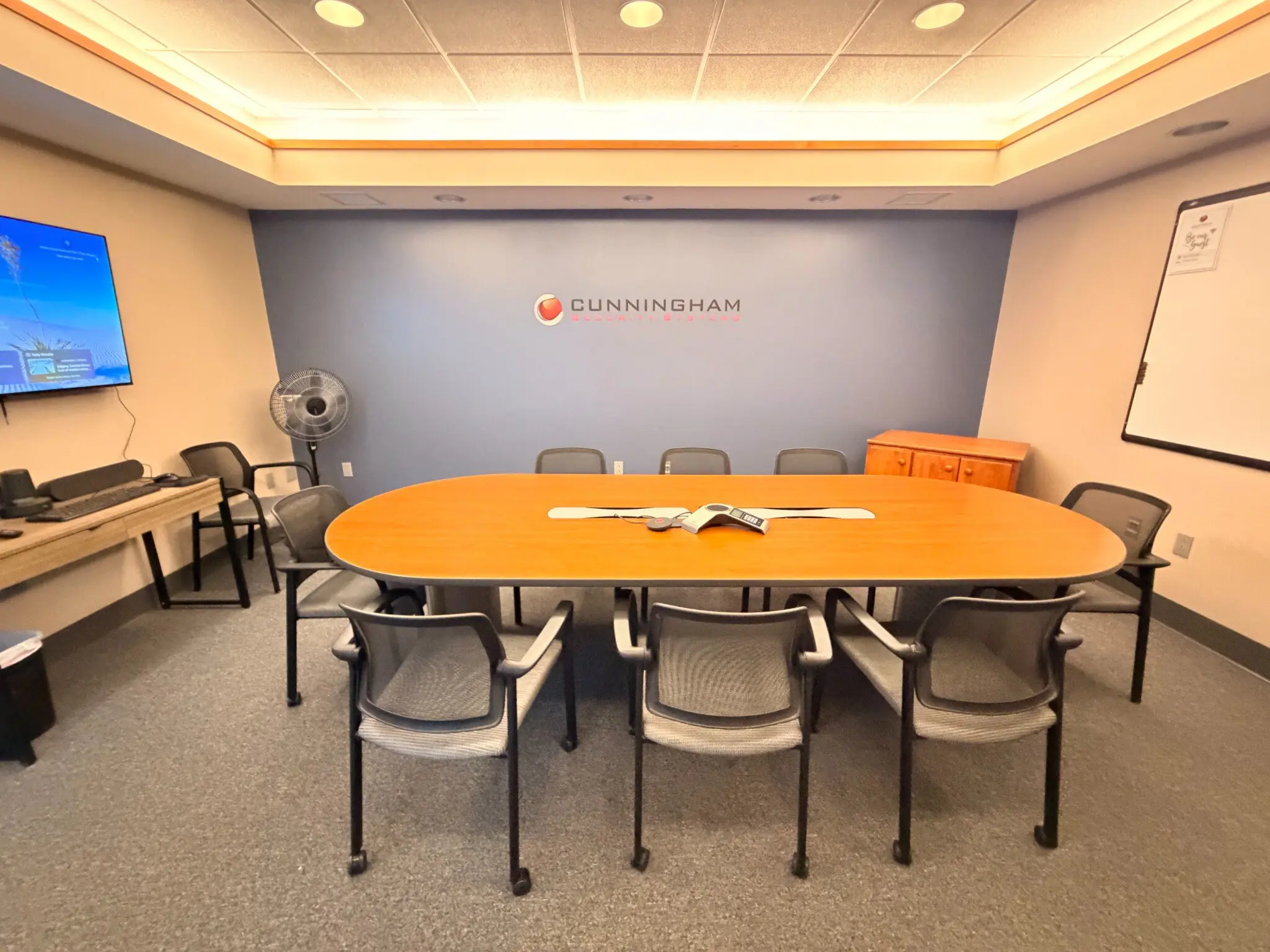 The Falmouth conference room seen from the doorway, with a wall-mounted display, whiteboard and conference phone